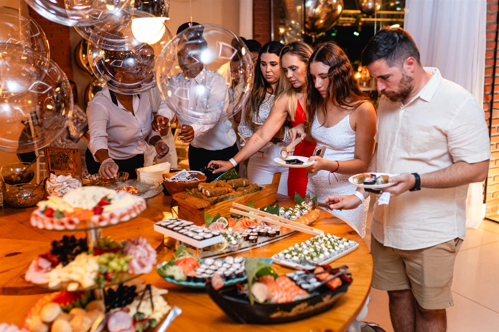 Convidados se servindo no buffet de sushi e frios da festa